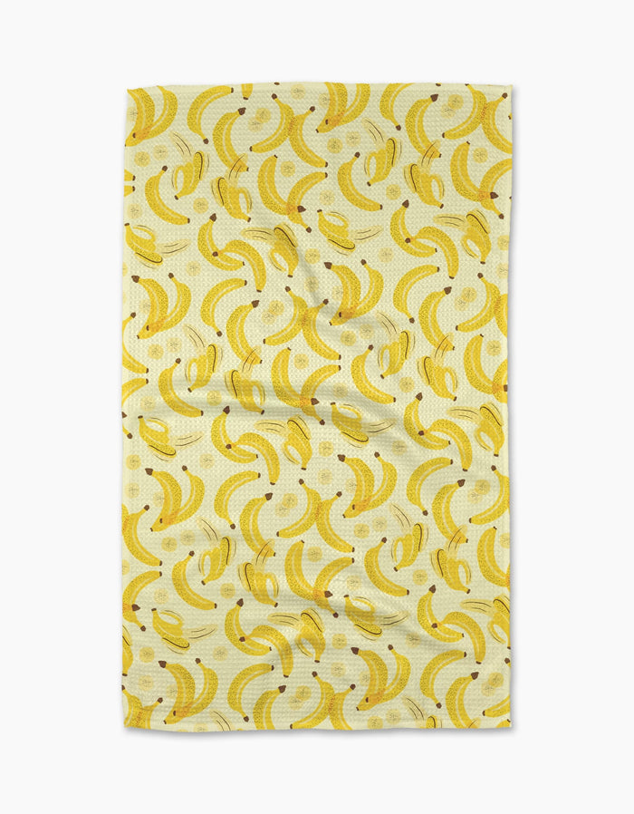 The A Bunch of Bananas Tea Towel by Geometry features a repeating yellow banana pattern on a light Geoweave fabric, shown slightly wrinkled against a plain white background.