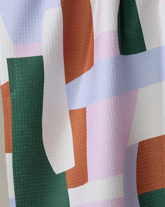 A close-up of the Abstract Collage fabric by Claire Iglesias, showcasing an abstract geometric pattern in green, rust orange, lavender, white, and light pink—ideal as a recycled kitchen towel or absorbent dish towel.