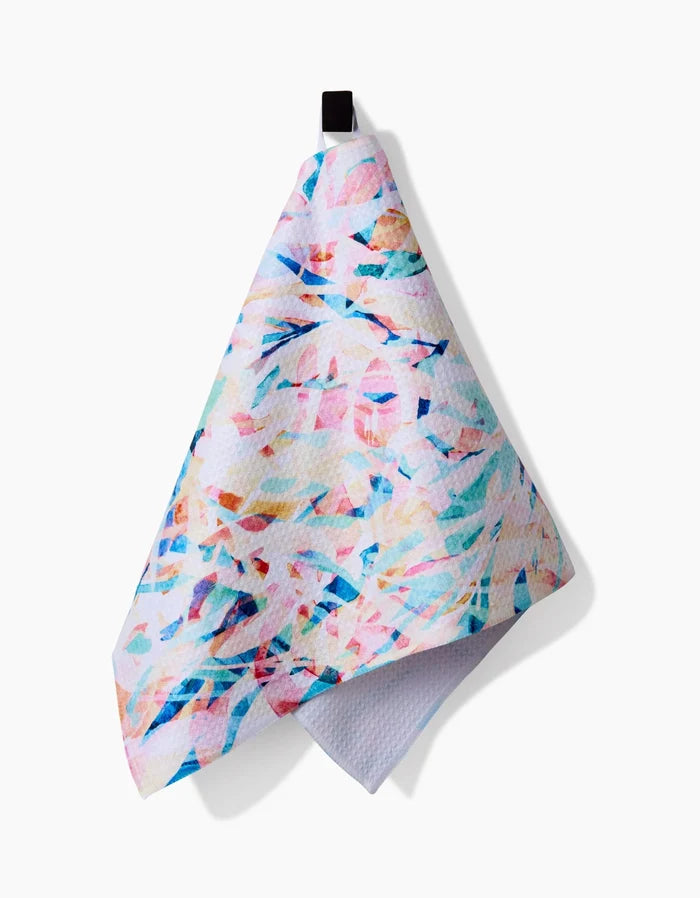 The Rachel Parker Abstract Jungle bar towel features pastel pink, blue, and teal abstract patterns on Geoweave fabric made from recycled materials, hanging by a black loop against a white background.