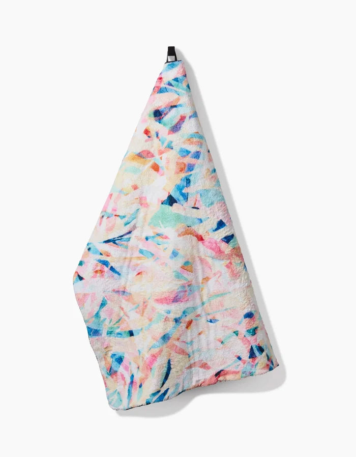 The Rachel Parker Abstract Jungle towel features a vibrant pastel abstract pattern and ultra-absorbent fabric, shown hanging from a black loop against a white background.