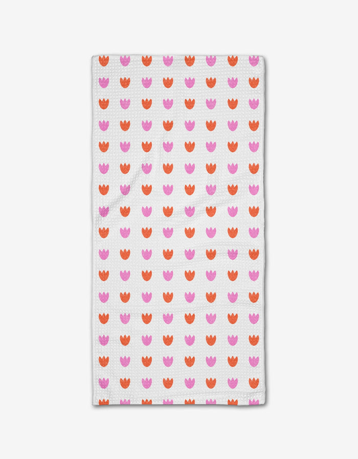 The Addison bar towel by Amy MacCready is a rectangular white towel featuring rows of pink and orange tulip-like shapes, crafted from innovative Geoweave fabric.