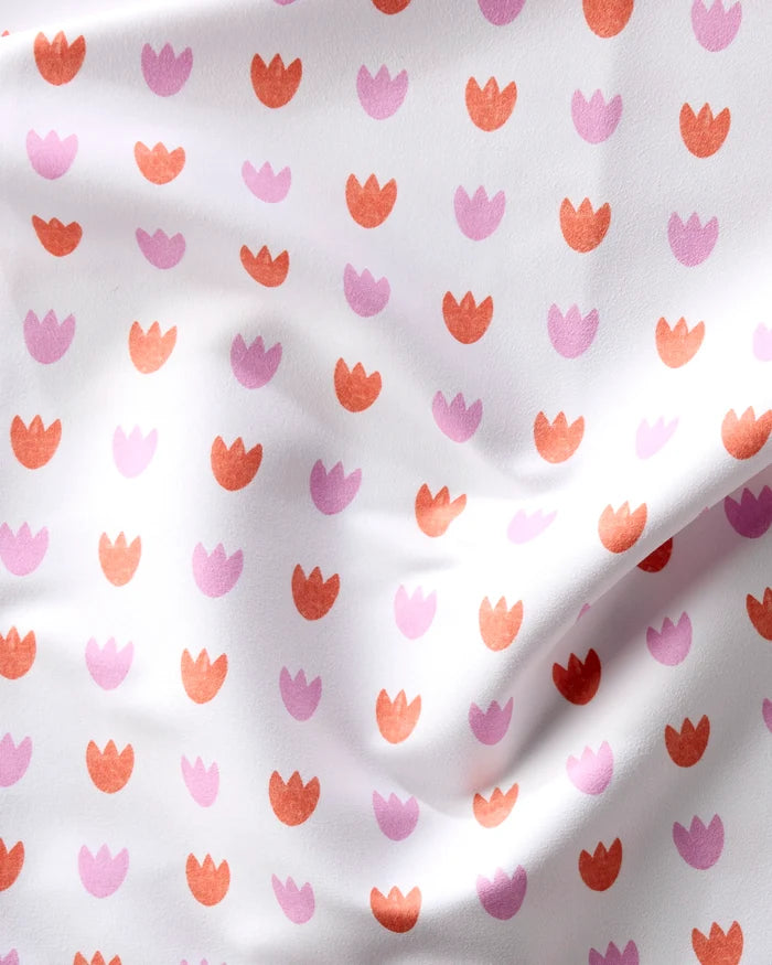 The Addison napkin by Amy MacCready features white fabric with a repeating pink and orange stylized tulip pattern. Its absorbent material and smooth texture make it a charming addition to any dinner napkin set.