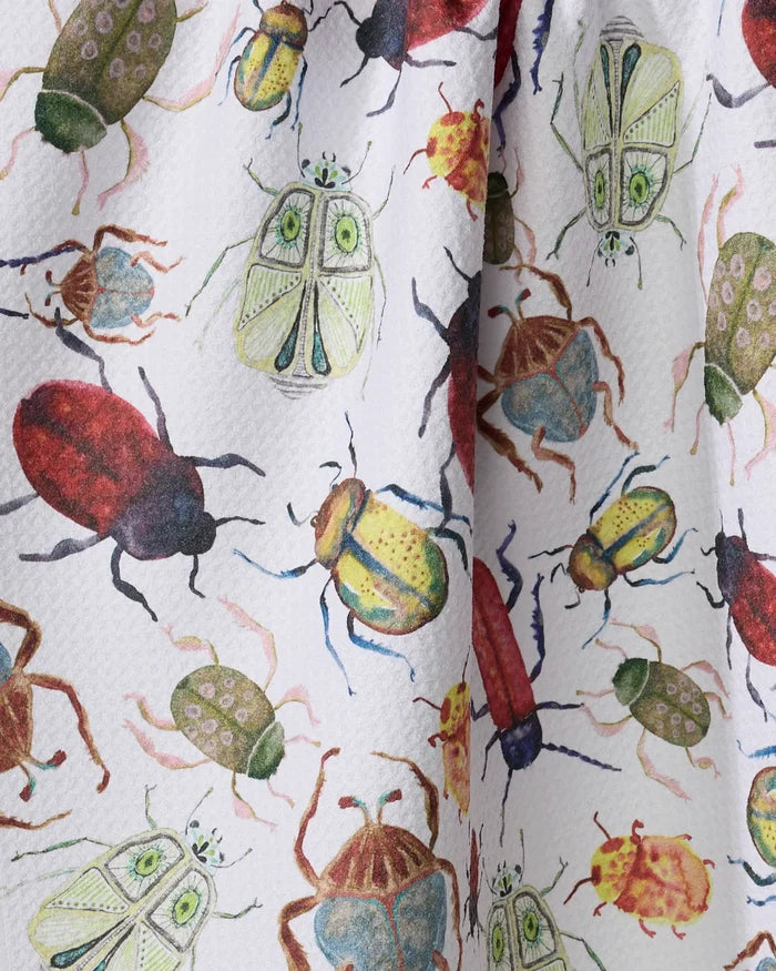 A close-up of the Taryn Brennan "African Beetles" tea towel, showcasing a colorful, detailed pattern of illustrated beetles and insects on a white background.