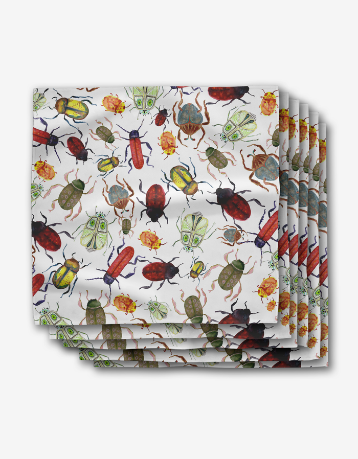 The Taryn Brennan “African Beetles” dinner napkins feature colorful beetle and bug illustrations on white Geosuede fabric made from recycled materials.