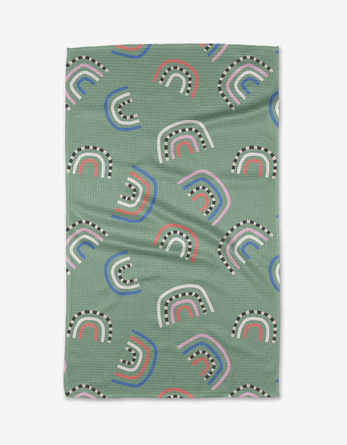The After the Rain tea towel by Claire Iglesias is a green, rectangular towel with abstract rainbow shapes in blue, red, pink, black, and white, made from ultra-absorbent recycled materials.