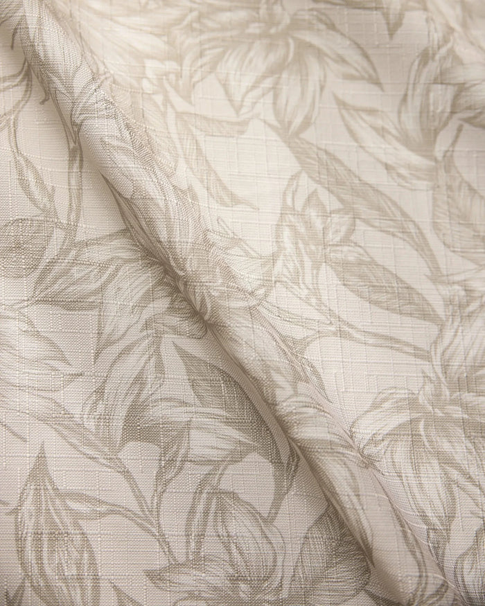 The Geometry Alba table runner features a light, stain-resistant fabric with a subtle floral leaf pattern and textured grid-like background for an elegant drape.