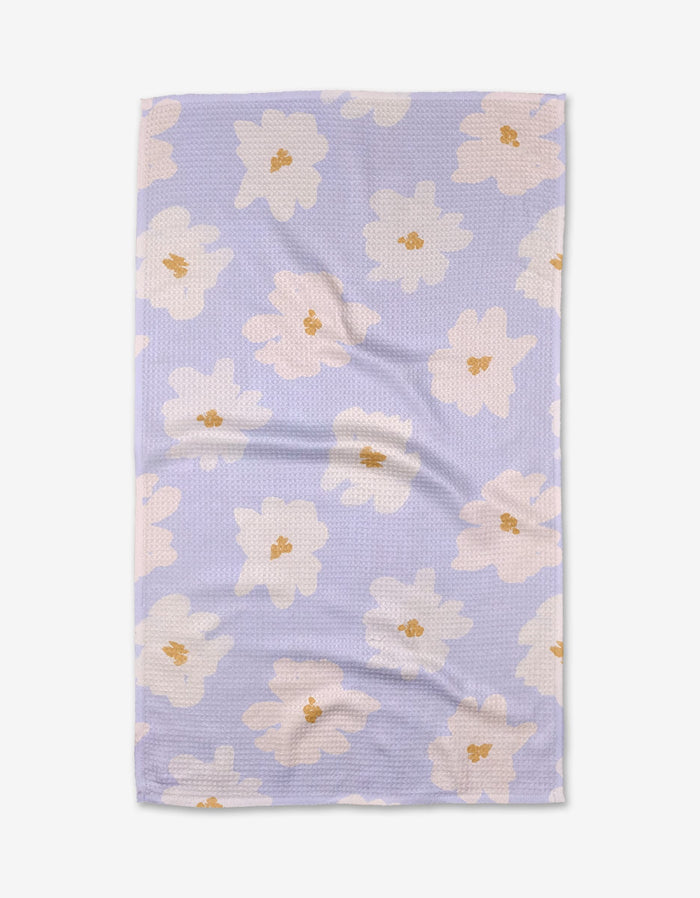 The Alpine Blooms tea towel by Mandy Arroyo features a rectangular shape in light purple Geoweave fabric with a textured surface and large white and beige flowers with yellow centers, shown on a white background.