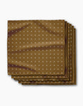 The Amber Stitch napkin by Geometry features brown Geosuede fabric with a subtle white X pattern, neatly folded into four layers and displayed on a white background.