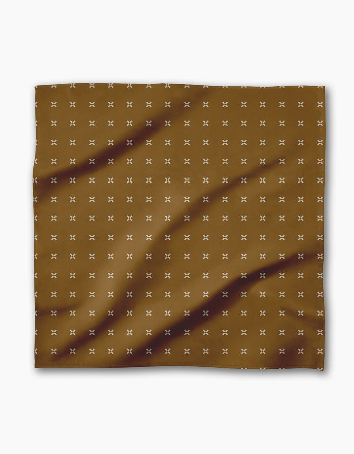 The Geometry Amber Stitch is a brown rectangular Geosuede cloth adorned with small white X patterns and subtle dark brown diagonal streaks.