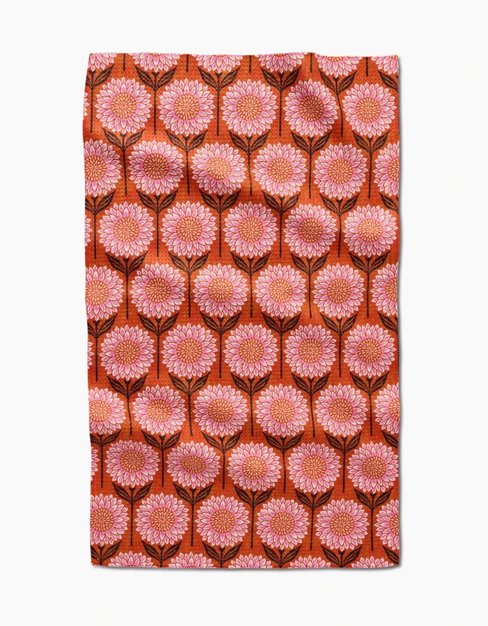 The Amy MacCready Amber tea towel is made from recycled materials and features large pink and orange flowers with black stems on deep orange, forming a symmetrical, ultra-absorbent surface.