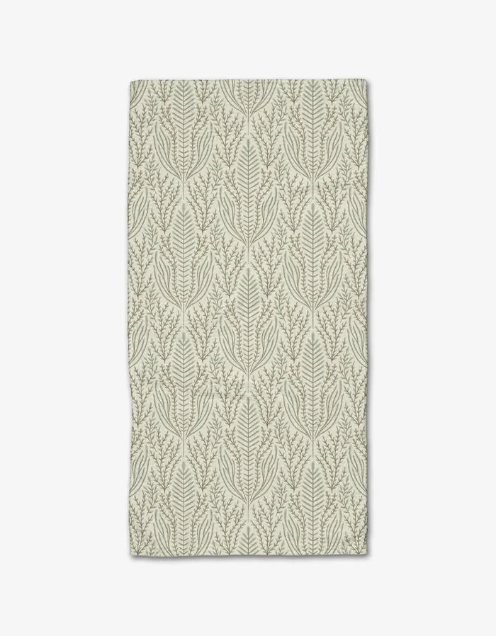 The Amberlin towel by Amy MacCready is a rectangular beige bar towel crafted from recycled materials, featuring symmetrical green leafy branches and vines that stand out against the light background.
