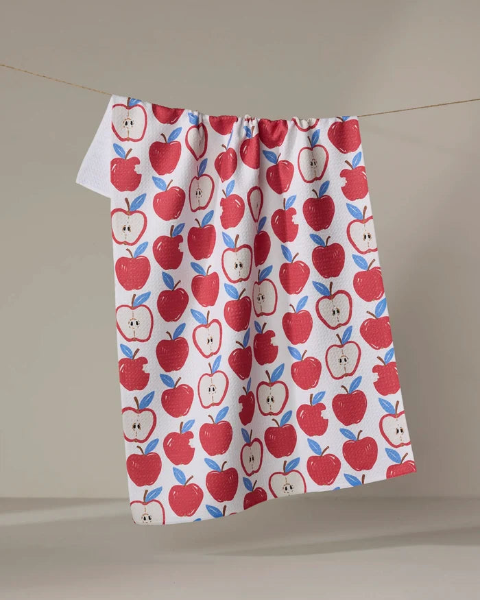 The Apple A Day tea towel by Hufton Studio features red apples and green leaves on white, hanging against a neutral background. Made from recycled materials, this absorbent towel brings eco-friendly charm to your kitchen.
