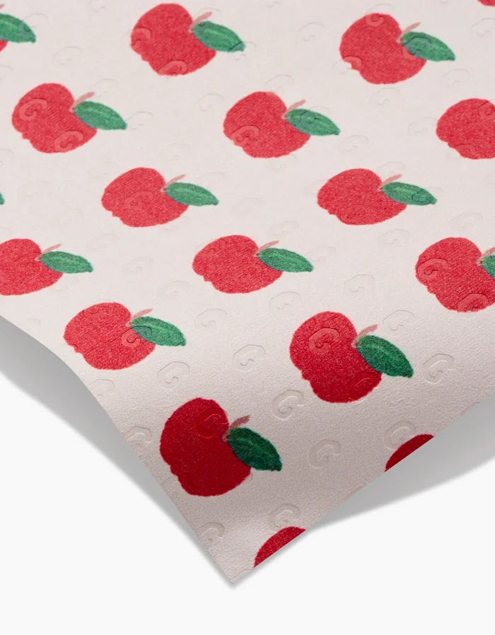 Apple Grove by Brittany Jepsen is a white sheet featuring a red apple and green leaf pattern, made with eco-friendly materials. It includes a subtle embossed “G” design.