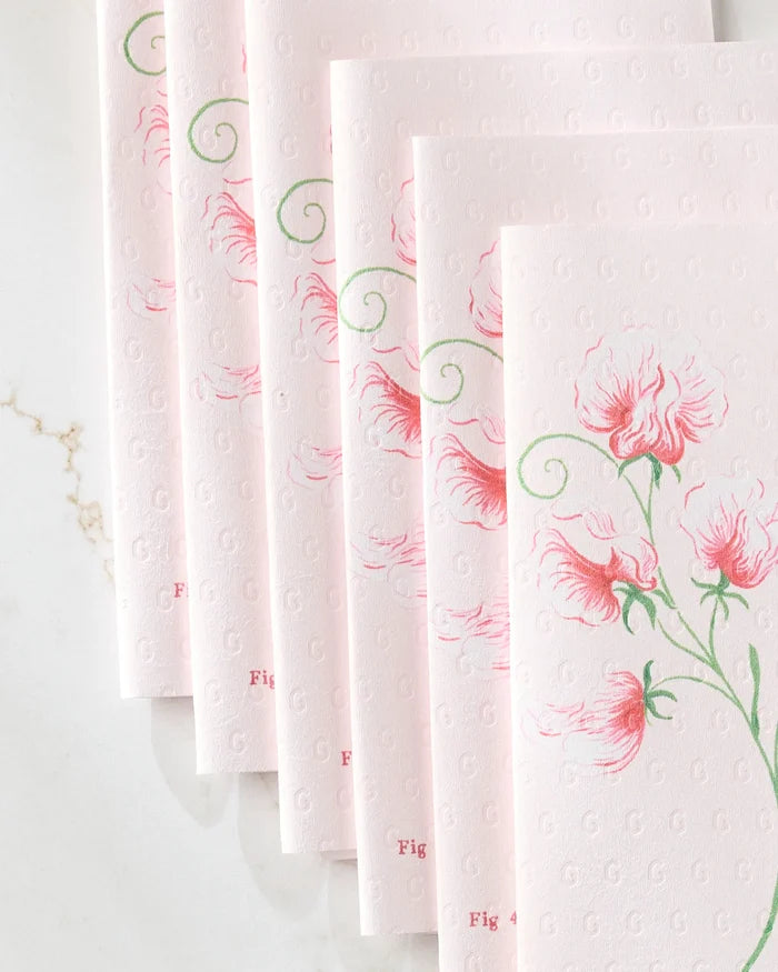 Six pale pink April Sweet Pea cards by Linda Fox, embossed with light pink floral designs and green stems, are fanned out on a white marble surface. The subtle G pattern and Fig 4 text suggest an elegant recycled paper towel alternative.