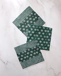 Three green Geometry Arbusto absorbent kitchen towels with white floral and stripe patterns are arranged on a white marble surface—two feature both stripes and flowers, while one displays only the floral design.