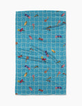 The Geometry At The Pool beach towel features a blue and white grid design with colorful poolside illustrations, made from ultra-absorbent Geoweave fabric for quick drying and comfort.