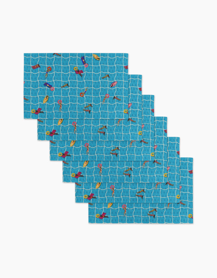 Six At The Pool rectangular blue reusable placemats by Geometry, each with a swimmers, ducks, and flamingos pool pattern over white tile-like grid lines—an eco-friendly alternative to Not Paper Towels.