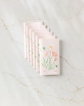 A stack of August Poppy seed paper cards by Linda Fox, adorned with hand-drawn pastel flowers and green leaves, rests on white marble—evoking the charm of eco-friendly, sustainable gifting.