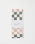 The GEOMETRY Autumn Checkers kitchen tea towel, featuring a white, gray, and light beige checkered pattern, is folded and wrapped with a white label reading "GEOMETRY Kitchen Tea Towel" on a white background.