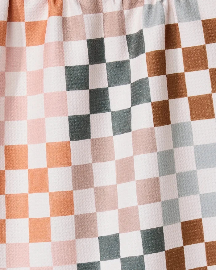 A close-up of the GEOMETRY Autumn Checkers towel shows its ultra-absorbent, crinkled fabric with a checkered pattern in muted pink, brown, gray, and white. Even lighting highlights the unique texture and evenly spaced squares.