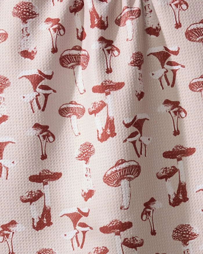 The Geometry Autumn Mushrooms tea towel features red mushroom illustrations on a textured white surface and is made from recycled materials.