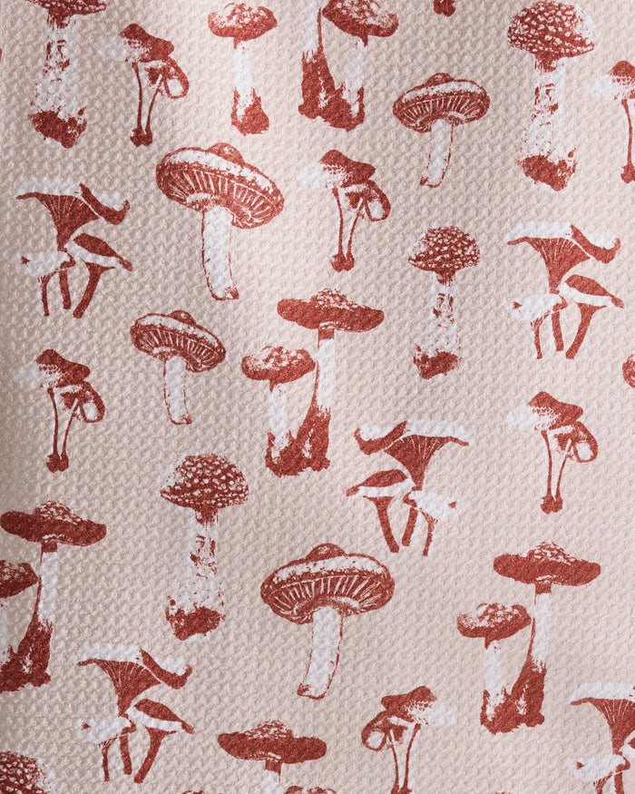 The Autumn Mushrooms towel by Geometry features a repeating pattern of brown mushrooms in various shapes and sizes on a light beige background—perfect as an ultra-absorbent or recycled kitchen towel.