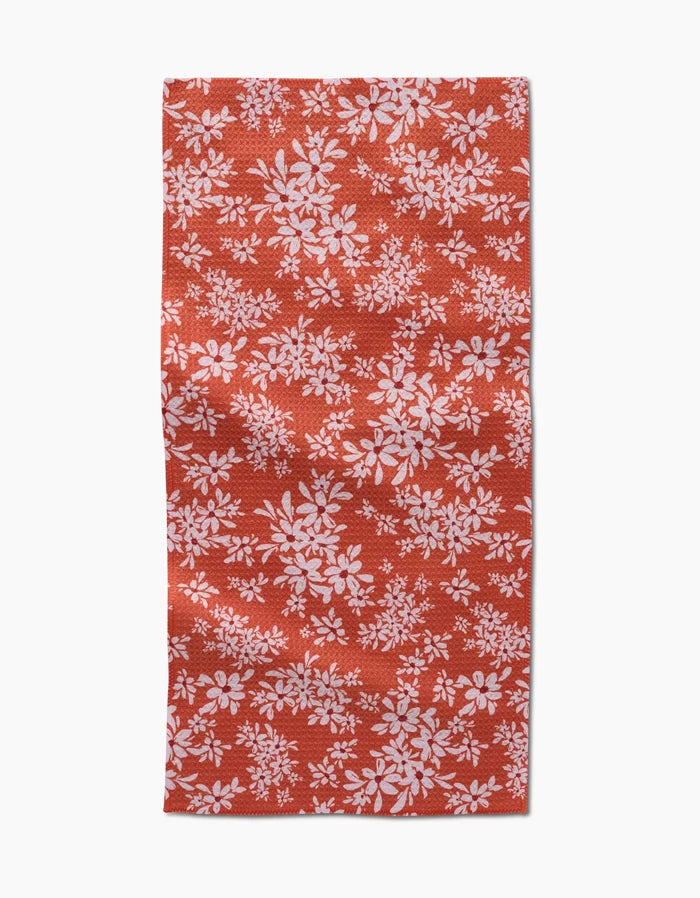 The Autumn Reverie by Ashley Celena is a red rectangular towel with a white floral pattern of scattered leaves and flowers. The ultra-absorbent fabric looks slightly wrinkled and is shown against a white background.