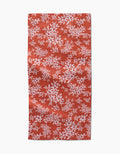 The Autumn Reverie by Ashley Celena is a red rectangular towel with a white floral pattern of scattered leaves and flowers. The ultra-absorbent fabric looks slightly wrinkled and is shown against a white background.