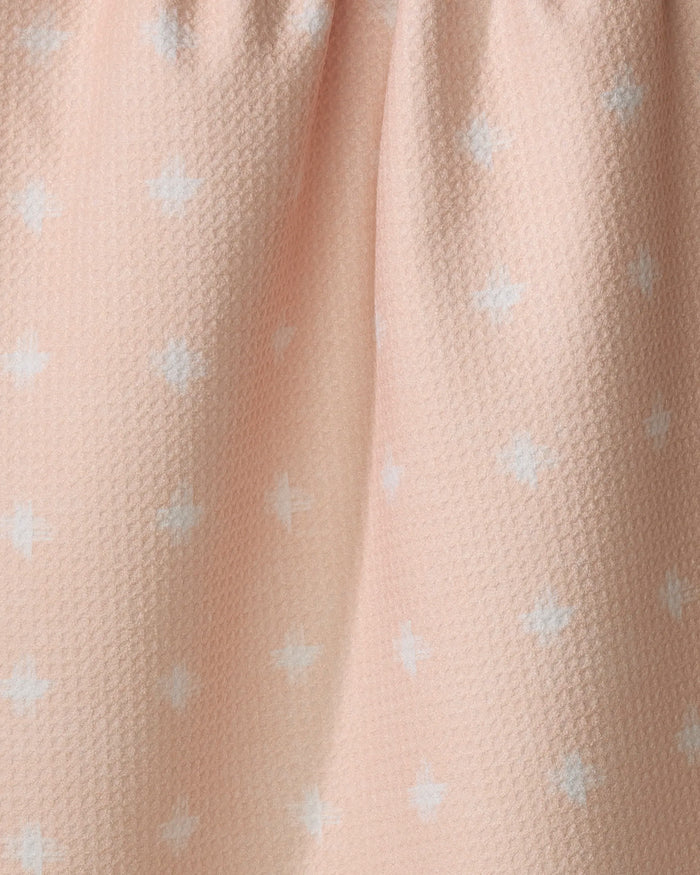 The Aveline kitchen towel by Amy MacCready features a light pink, recycled fabric with a softly pleated top and a textured surface adorned with small white plus signs in a subtle repeating pattern.