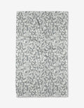 The Babys Breath Geoweave fabric by Katie OShea features a white background with gray and blue leaf and vine patterns, laid flat to showcase its intricate botanical design and ultra-absorbent, eco-friendly qualities.