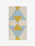 The GEOMETRY Balanced Blue blanket features a geometric pattern of yellow and blue triangles and diamonds on a cream background, with bold, symmetrical shapes running vertically. Made with ultra-absorbent Geoweave technology.