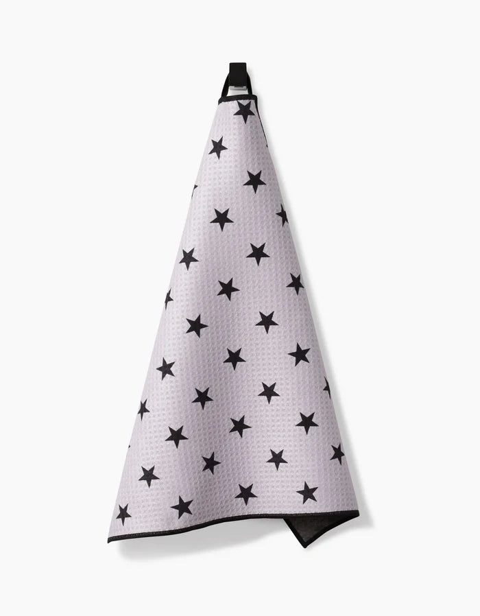 The Geometry Bark Paw Towel, made from ultra-absorbent Geoweave fabric, features a white texture with black star patterns and hangs by a black loop against a plain white background.