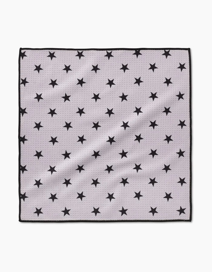 The Geometry Bark Paw Towel is a square, light gray towel made from ultra-absorbent Geoweave fabric, featuring a thin black border and a repeating pattern of evenly spaced black stars, shown laid flat on a white background.