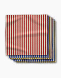 Geometrys Bauhaus Stripe dinner napkins, made from recycled materials, feature vertical red and beige stripes above layers with blue and yellow stripes, all displayed on a white background.