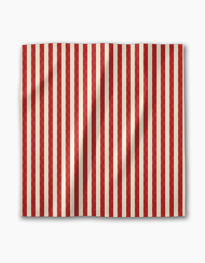 The Geometry Bauhaus Stripe is a rectangular dinner napkin with alternating vertical red and beige stripes, crafted from soft Geosuede fabric, and shown slightly wrinkled on a plain white background.