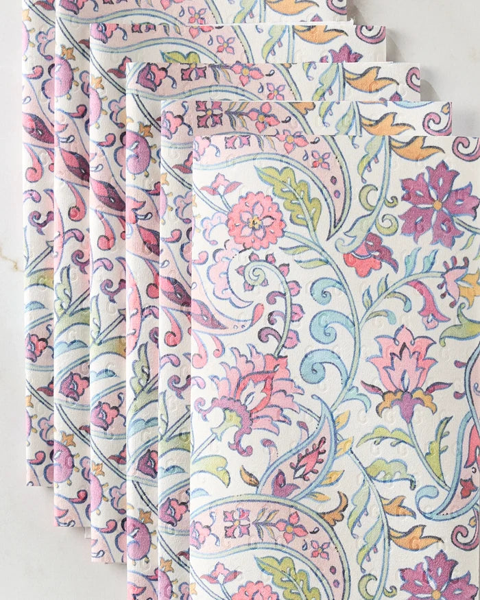 Six intricately folded Bazaar napkins by Maayan Alper-Swan, featuring a vibrant floral and paisley design in pink, purple, yellow, and green—an eco-friendly alternative to kitchen towels—displayed on a light surface.