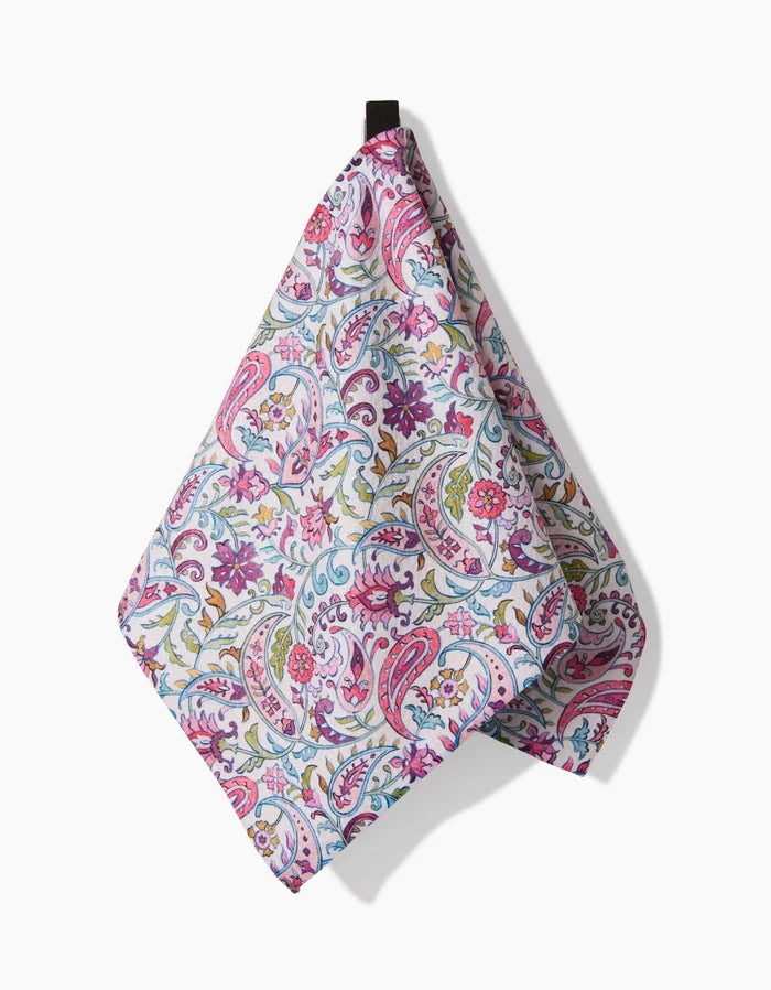 The Bazaar towel by Maayan Alper-Swan features a colorful paisley and floral design in pink, blue, green, and yellow. Made from ultra-absorbent Geoweave fabric, it hangs by a small black loop against a white background.