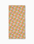 The Geometry Beachy Tile bar towel is made from Geoweave fabric and features a repeating pattern of small, colorful squares in orange, pink, green, and yellow on a light background.