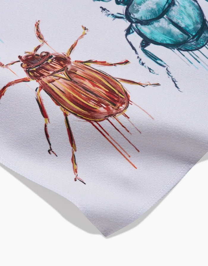 Close-up of Taryn Brennans Beetles napkins made from Geosuede, showcasing colorful, detailed painted beetles with drips on a white background. These eco-friendly napkins feature vibrant insect illustrations.