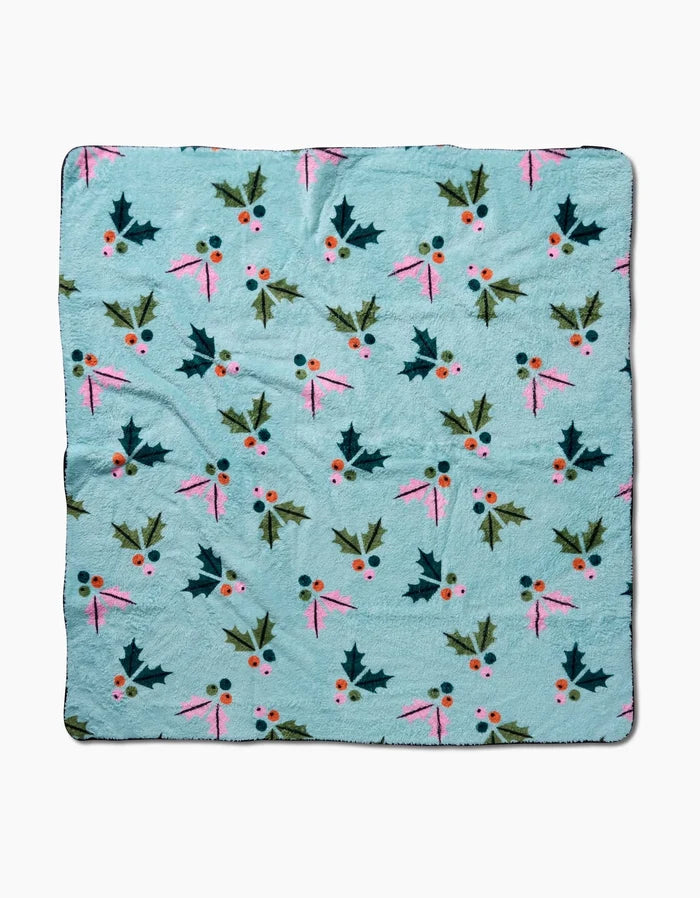 The Berries Mint dog towel by Megan Roy is a light blue, ultra-absorbent towel with holly leaves, red berries, and pink ribbons in a repeating pattern, shown flat on a white background.