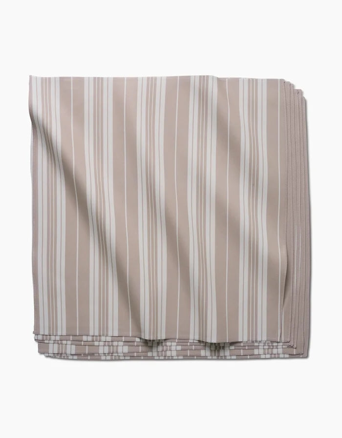 The GEOMETRY Betty Beach dinner napkin set features neatly folded Geosuede fabric with vertical white and beige stripes, displayed against a white background.
