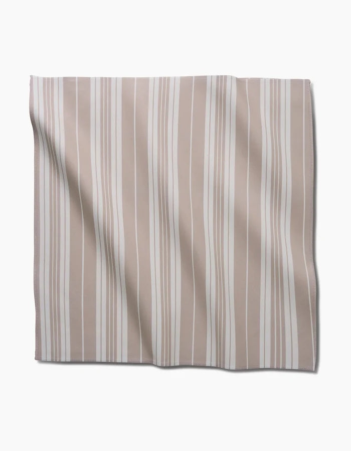 The GEOMETRY Betty Beach Dinner Napkin Set, made from Geosuede fabric with beige and white vertical stripes, is laid flat on a white background, showing soft folds and slight wrinkles.
