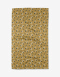 Betty by Charlie Rowan Designs is a mustard yellow Geoweave™ fabric with small white flowers and green leaves, shown flat against a white background with some visible creases.