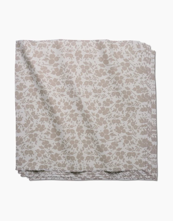 The GEOMETRY Bettys Buds napkin, crafted from Geosuede fabric with a beige and white floral print, is folded and displayed against a white background.