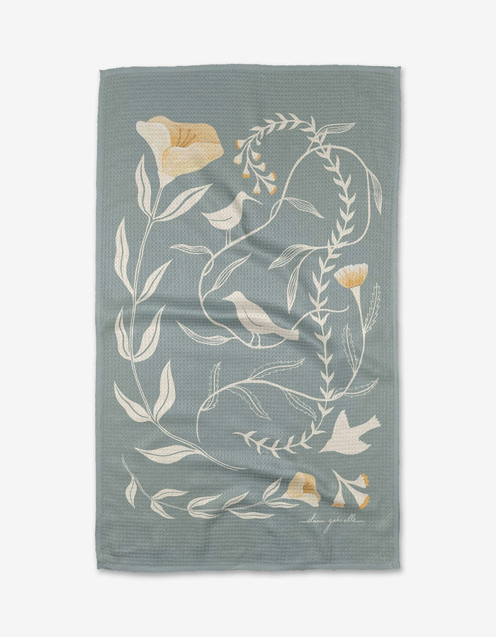 Birdsong by Elana Gabrielle is a light blue textured tea towel with white and yellow floral vine designs, crafted from eco-friendly Geoweave fabric and finished with the artist’s signature in the bottom right corner.