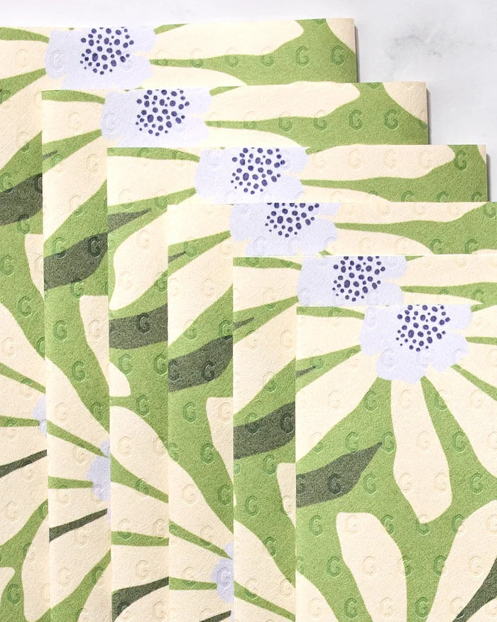 Five eco-friendly GEOMETRY Bliss and Bloom paper towels display a green and cream floral pattern with purple-centered flowers, arranged fanned-out and overlapping against a light background.