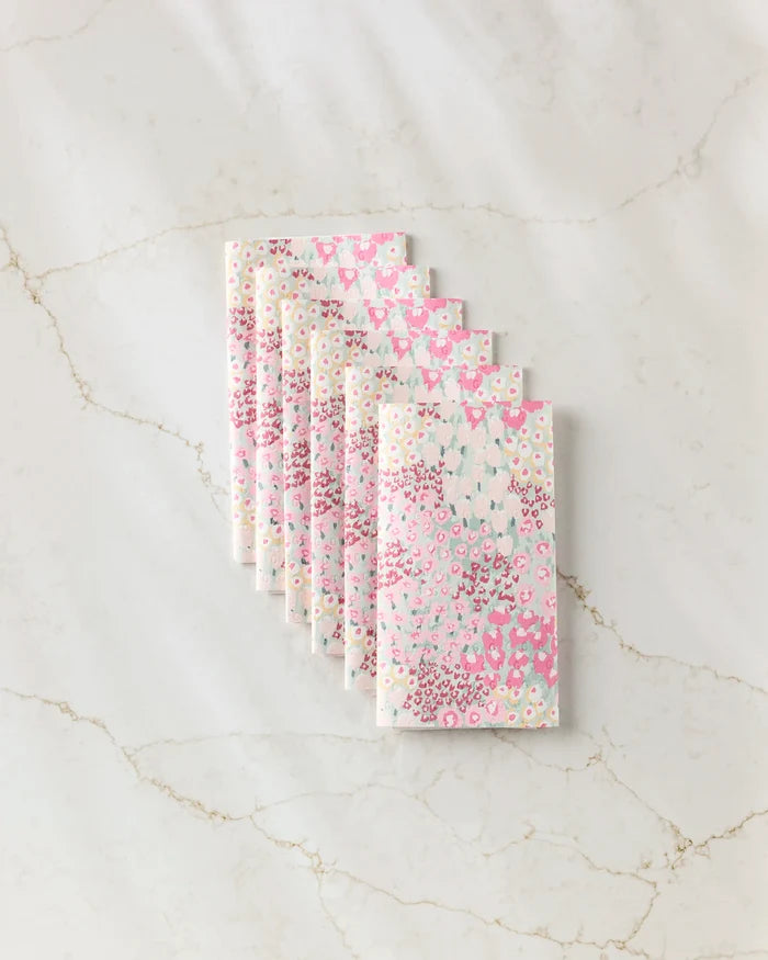 Seven folded reusable paper towels from Hufton Studio’s "Bloomed For Spring" collection, featuring pink, white, and yellow floral patterns, are neatly arranged in a fan shape on a white marble surface.