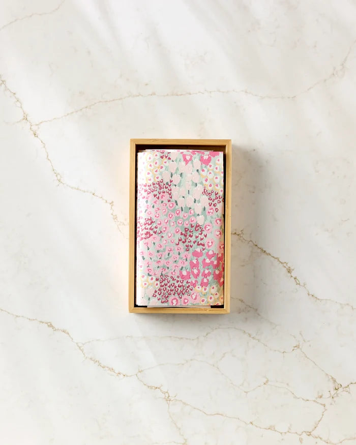 Hufton Studio's "Bloomed For Spring" features floral-patterned pink and white reusable paper towels in a rectangular wooden box, displayed on a white marble surface with light brown veining.