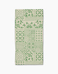 The Blossoming Bandanna Green Bar Towel by Geometry features a green patchwork of floral, geometric, and decorative designs on beige Geoweave fabric, shown flat against a white background.