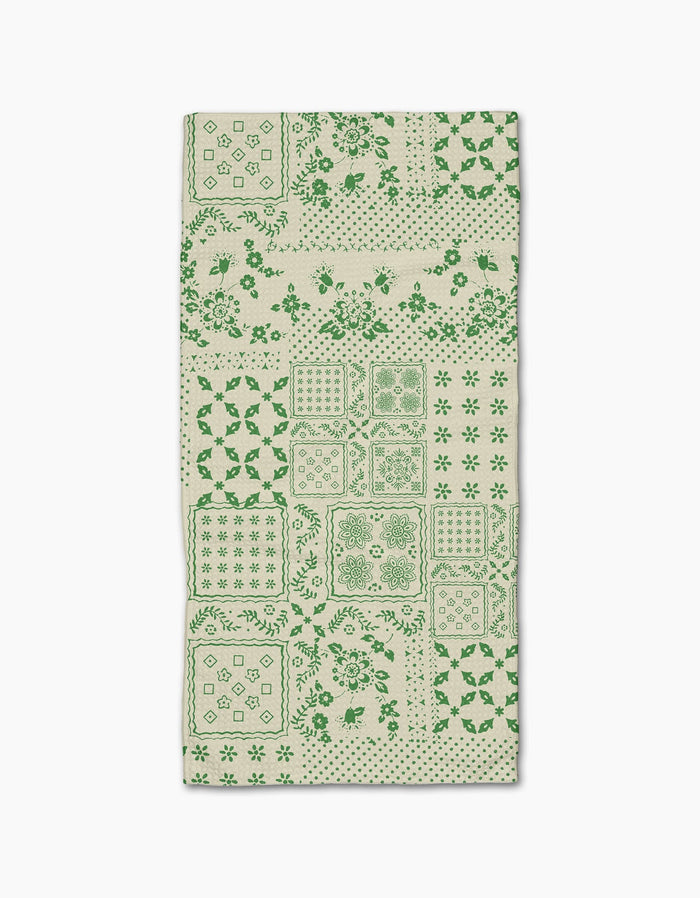 The Blossoming Bandanna Green Bar Towel by Geometry features a green patchwork of floral, geometric, and decorative designs on beige Geoweave fabric, shown flat against a white background.